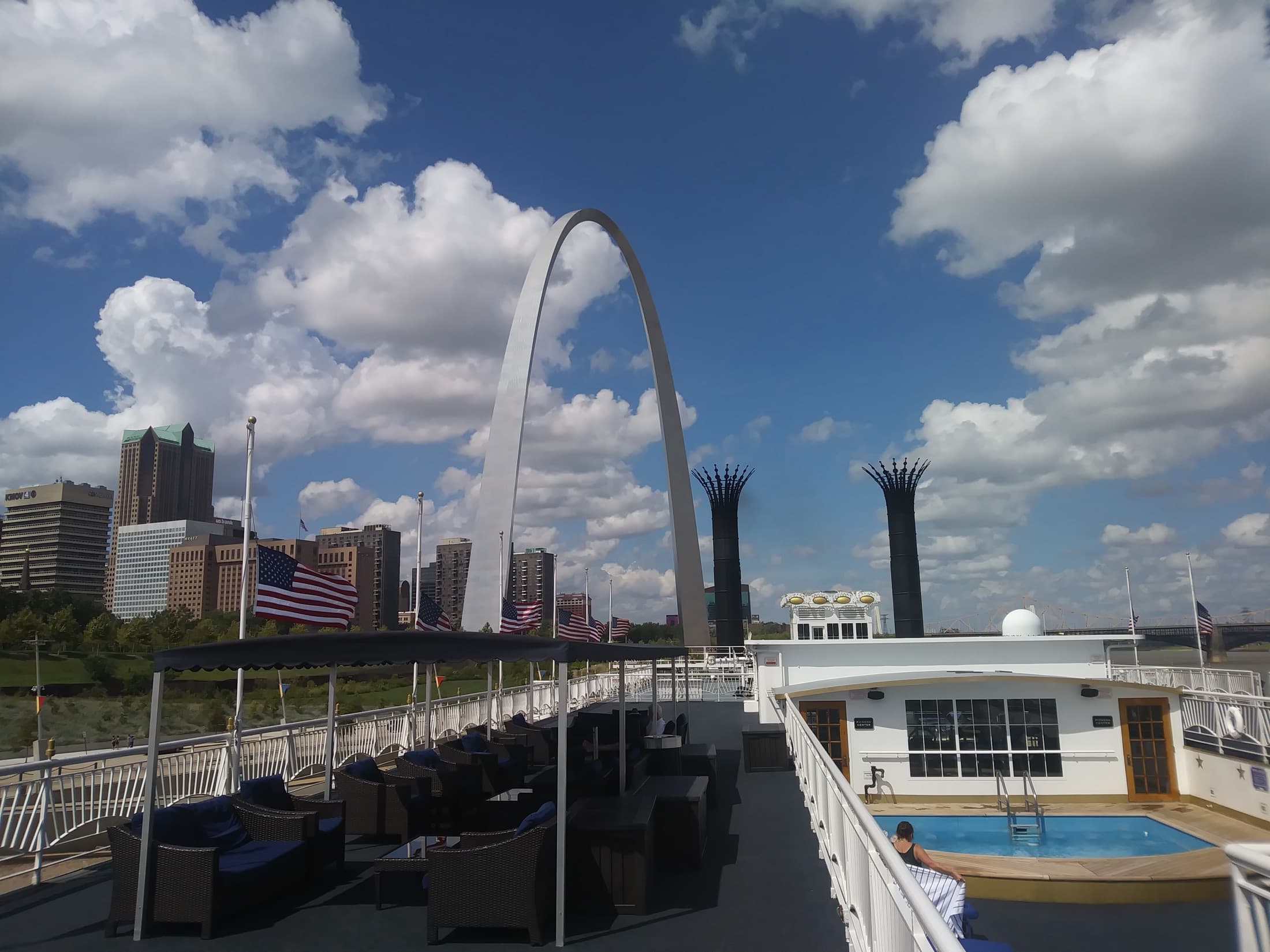 The Gateway Arch rising over the St. Louis riverfront in daylight, photographed from the Mississippi River, with the stainless-steel catenary arch against a blue sky in Gateway Arch National Park, Missouri.