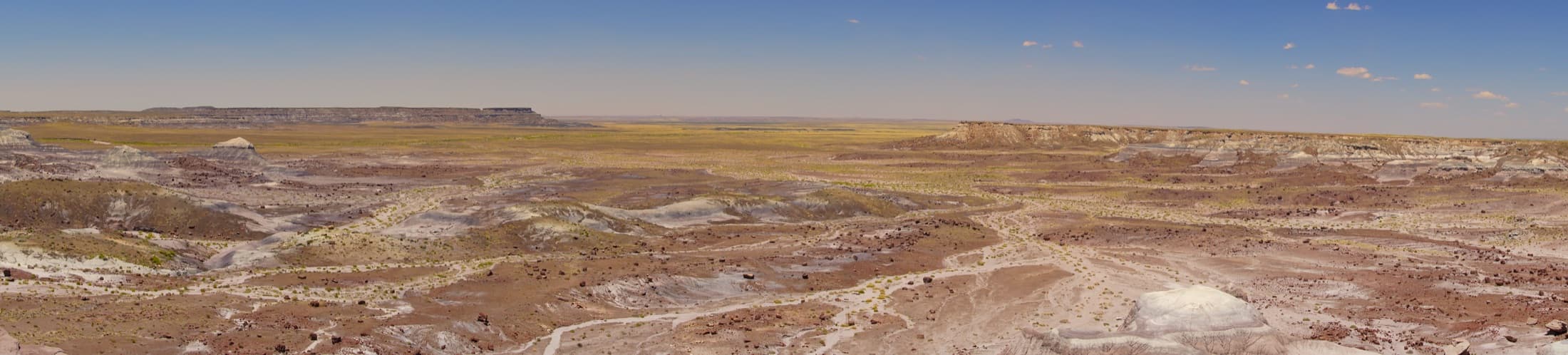 Wide panoramic view of the colorful badland hills and eroded geological formations of Petrified Forest National Park in Arizona under a clear sky