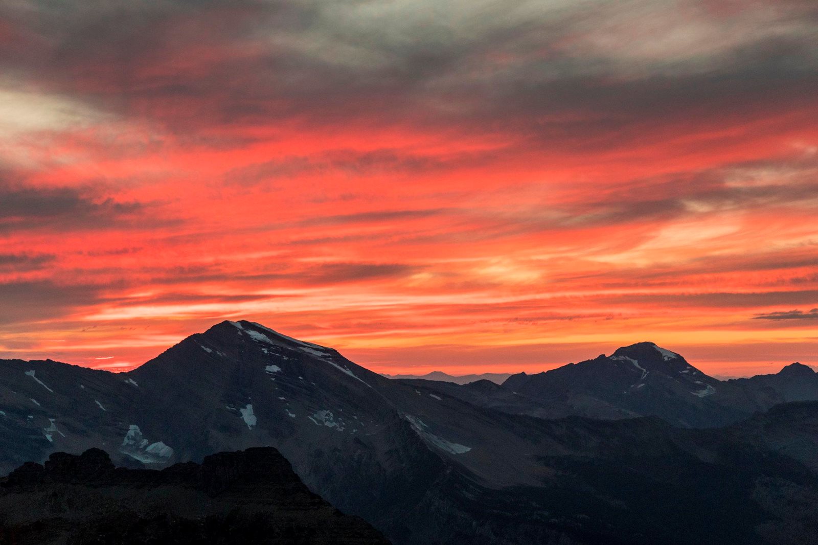Orange sunset clouds over Glacier National Park peaks