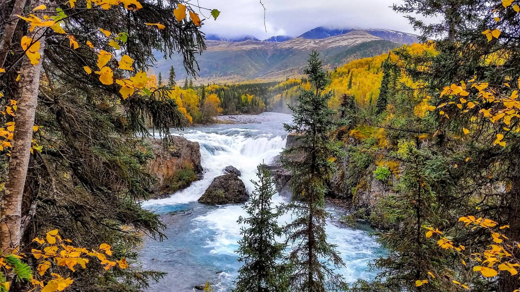 Tanalian Falls surrounded by fall forest and mountains