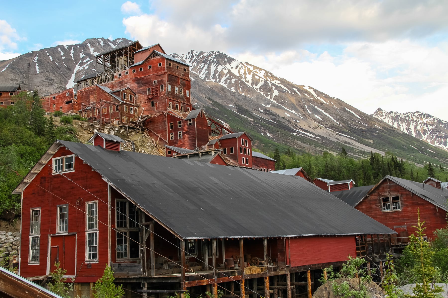 Historic red Kennecott Mill Town buildings with mountains behind them