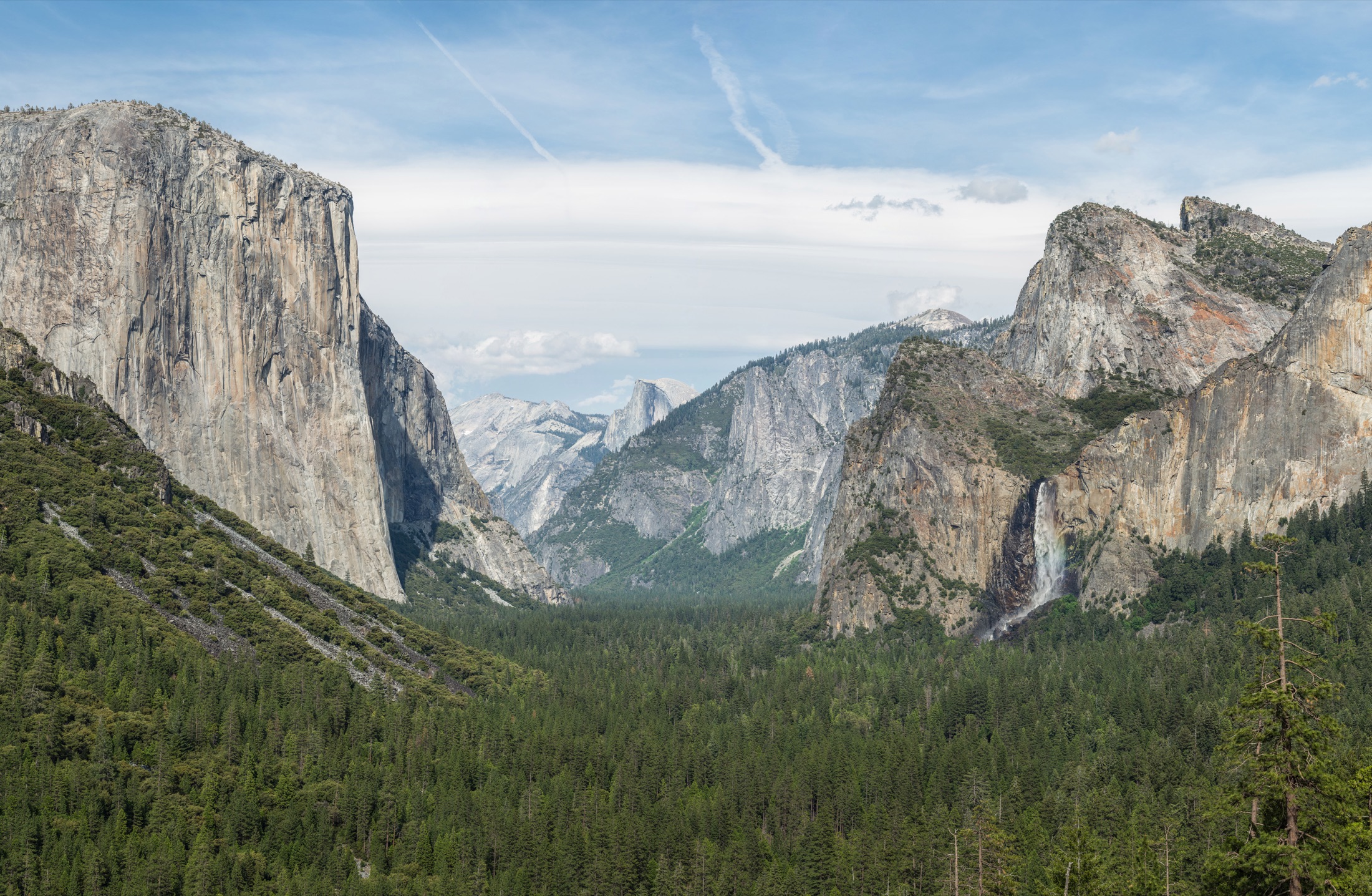 Yosemite Valley seen from Tunnel View, with El Capitan rising on the left, Bridalveil Fall on the right, and Half Dome in the distance under a clear sky